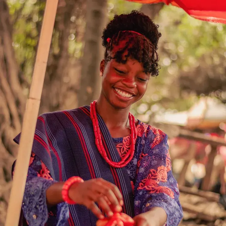 A trader laughing as she sorts tomatoes at her market stall.